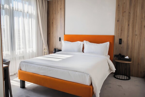 A hotel room with a bed, a bedside table, and a small round table with a lamp. - Afrosiyob Regency Hotel (Tashkent)