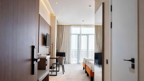 Ein Hotelzimmer mit Bett, Schreibtisch, Stuhl, Fernseher und Badezimmer.