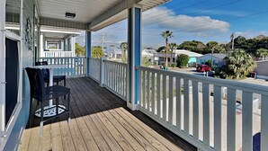 A covered porch with a wooden floor, white railings, and a table with chairs. - Gone Shellin' (Panama City Beach)