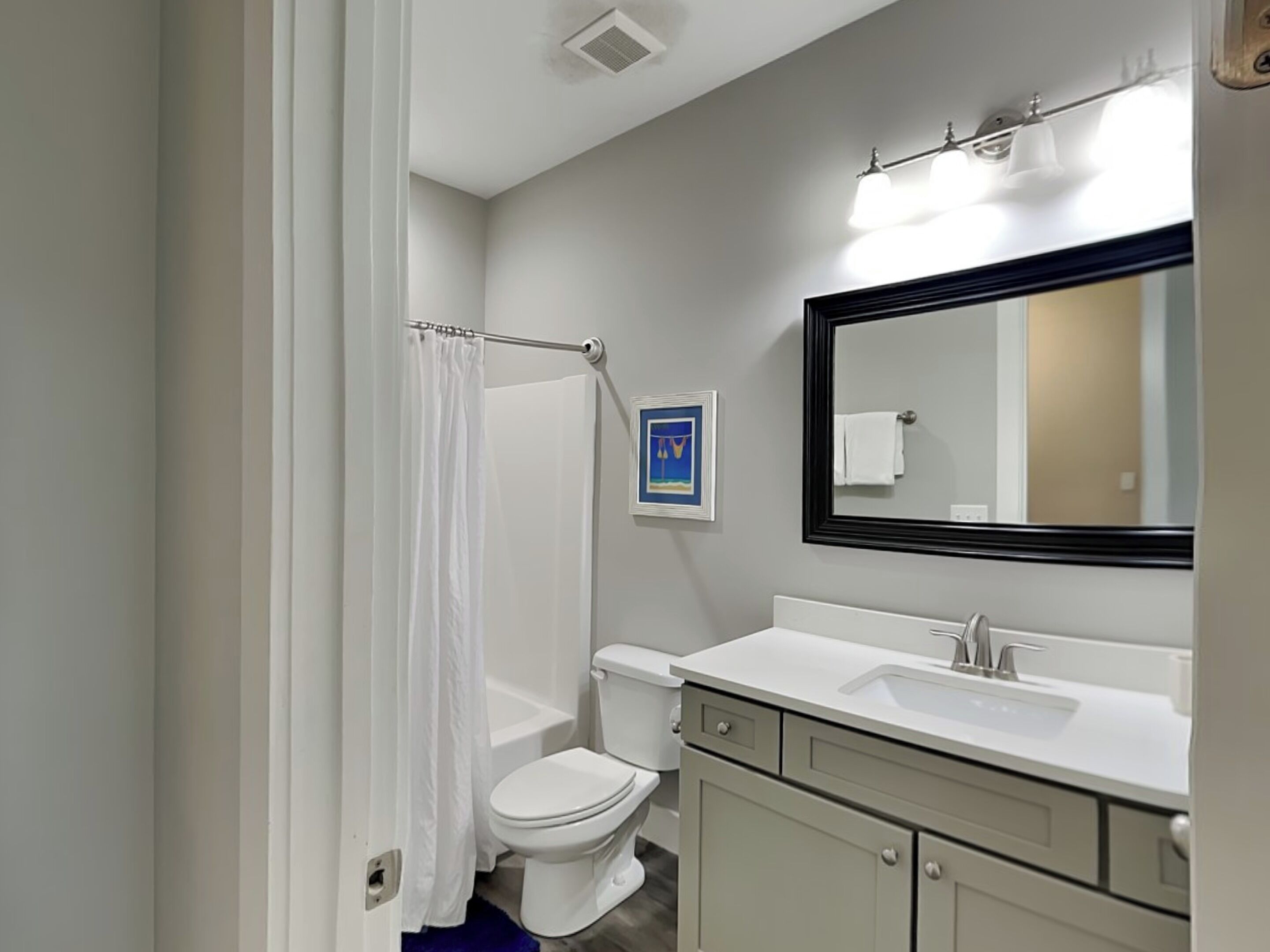 A bathroom with a white toilet, a bathtub, a sink, and a mirror.