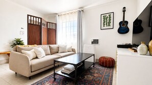 A living room with a sofa, coffee table, rug, and a guitar on the wall. - Downtown Studio FREE Parking & 1 mile to Beach & Convention Center (Long Beach)