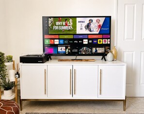 Ein Flachbildfernseher auf einer weißen Kommode mit goldenen Griffen, der einen Sportkanal anzeigt.