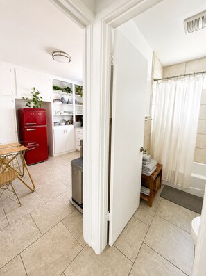 A compact kitchen with a red appliance, a dining area with a table and chairs, and a bathroom with a shower curtain. - Downtown Studio FREE Parking & 1 mile to Beach & Convention Center (Long Beach)