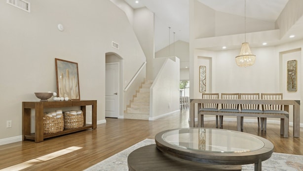 Un salon spacieux avec un banc en bois, une table basse en verre et un escalier menant à l’étage supérieur.