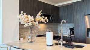 Een moderne keuken met donker houten kastjes, een roestvrijstalen koelkast en een centraal eiland met barstoelen.