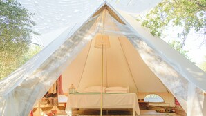 A tent with a bed, a lantern, and a small table. - Odyssey Eco Farm Glamping (Troizinia)