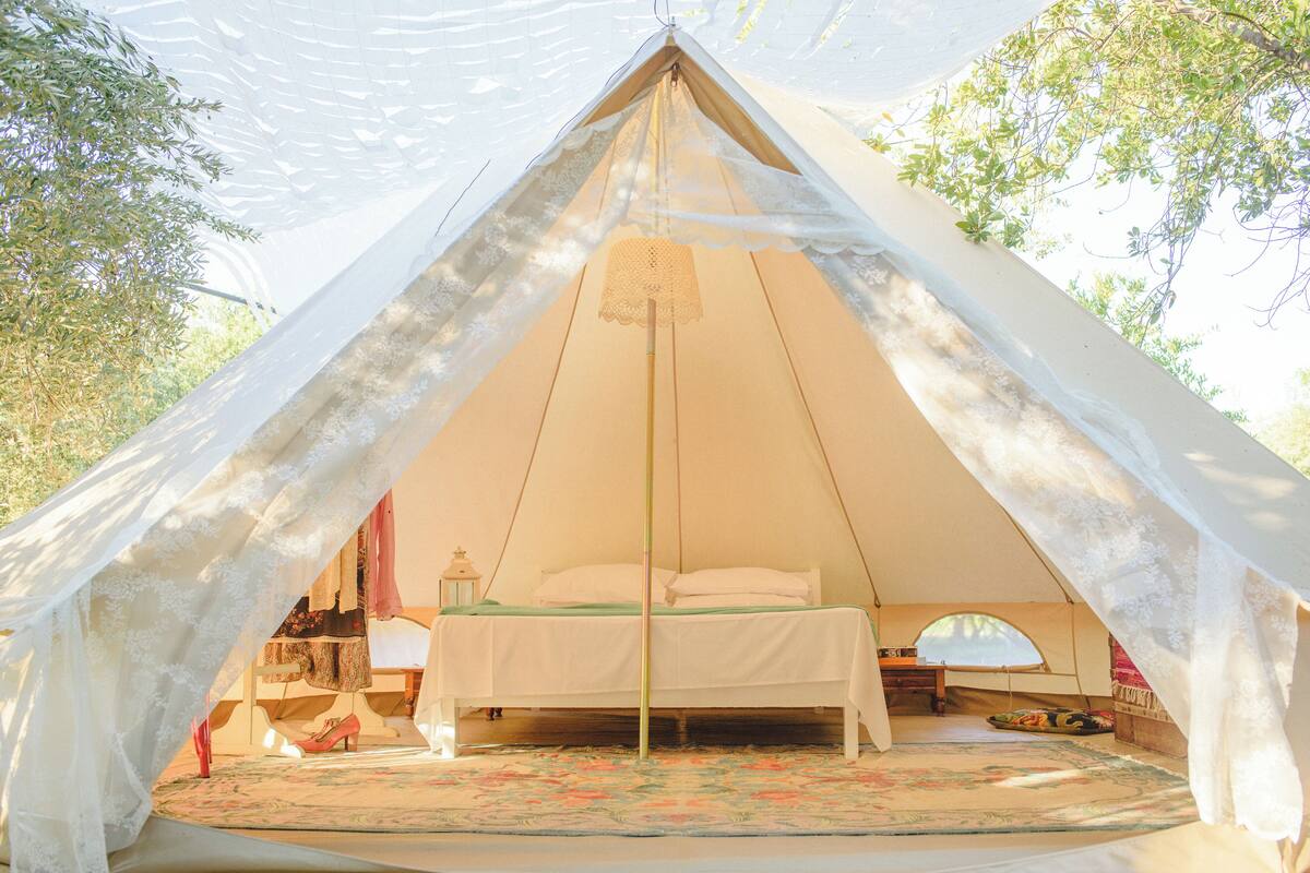 A tent with a bed, a lantern, and a small table.