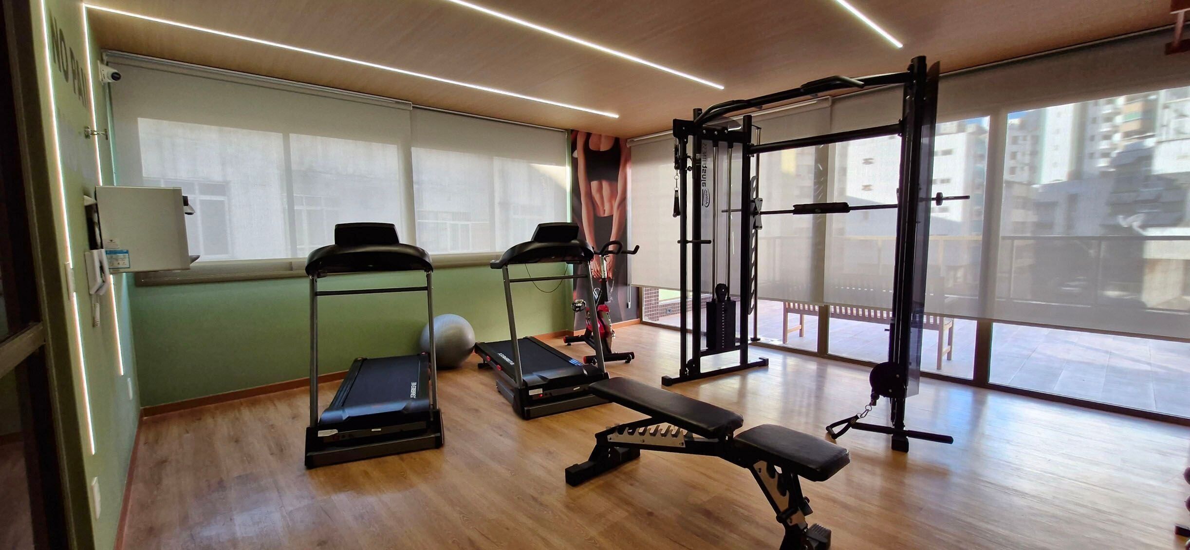 A gym with treadmills, a bench press, and a squat rack.