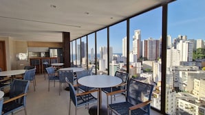 Une chambre d’hôtel moderne avec balcon, dotée de tables et de chaises, et offrant une vue sur la ville.