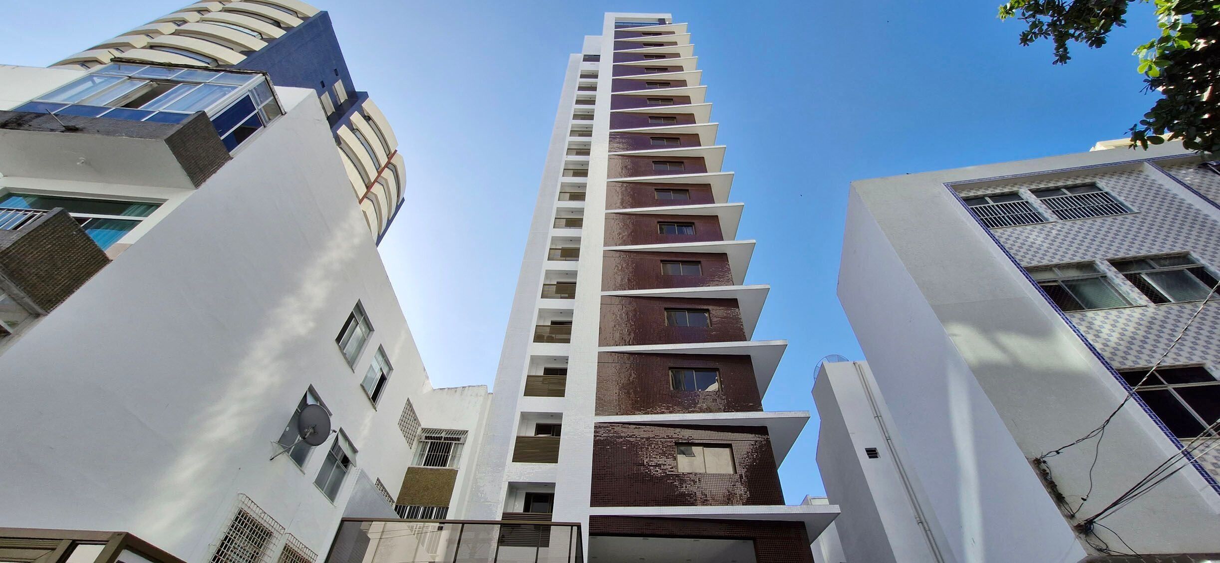 A modern high-rise building with multiple floors, featuring a mix of white and brown facades, and large windows.