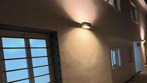 En bygning med en betonfacade, mange vinduer og udendørs belysning.