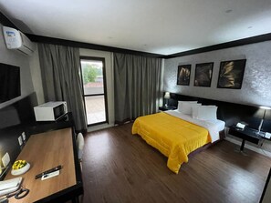A hotel room with a bed, a desk, a chair, a TV, a window with curtains, and artwork on the wall. - FARIA LIMA HOTEL COM VARANDA GARDEN  (São Paulo)