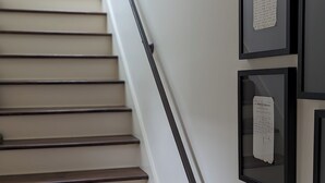 A staircase with wooden steps and a metal handrail, leading to a landing with framed documents on the wall. - Beautiful 2 Bedroom Apartment Farmhouse in Canton (Canton)