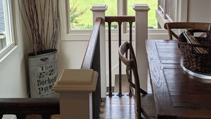 A dining area with a wooden table and chairs, a railing, and a view of a green landscape through large windows. - Beautiful 2 Bedroom Apartment Farmhouse in Canton (Canton)