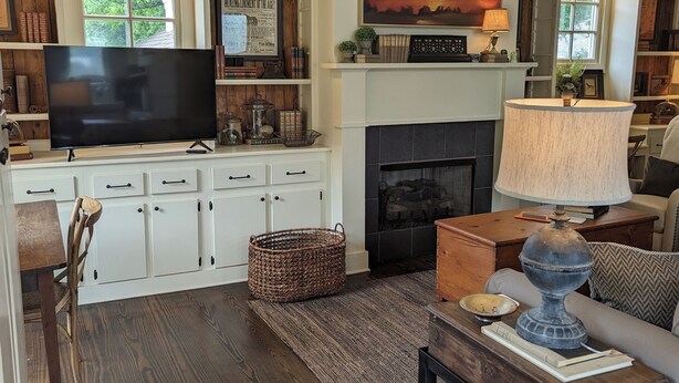 A cozy living room with a fireplace, wooden flooring, and a television. - Beautiful 2 Bedroom Apartment Farmhouse in Canton (Canton)