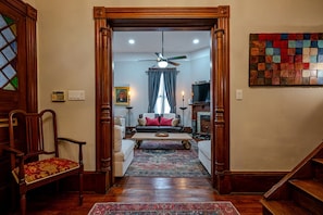A living room with a wooden staircase, a sofa, a coffee table, and a patterned rug. - Grant Park 4BR Victorian Retreat Walk to Zoo & BeltLine - Private Parking Deck (Atlanta)