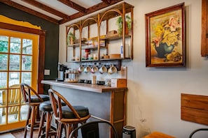 A cozy bar area with wooden stools, a coffee station, and a painting of flowers. - Grant Park 4BR Victorian Retreat Walk to Zoo & BeltLine - Private Parking Deck (Atlanta)
