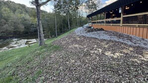 A building with a covered outdoor area, a gravel path, and a river in the background. - Amazing Waterfalls & Swim Hole at Dale Hollow Lake (albany)