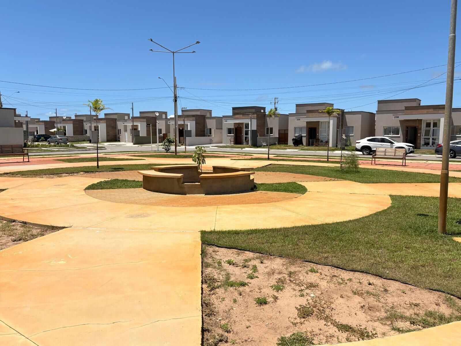 A modern residential area with a central circular plaza, paved walkways, and uniform apartment buildings.