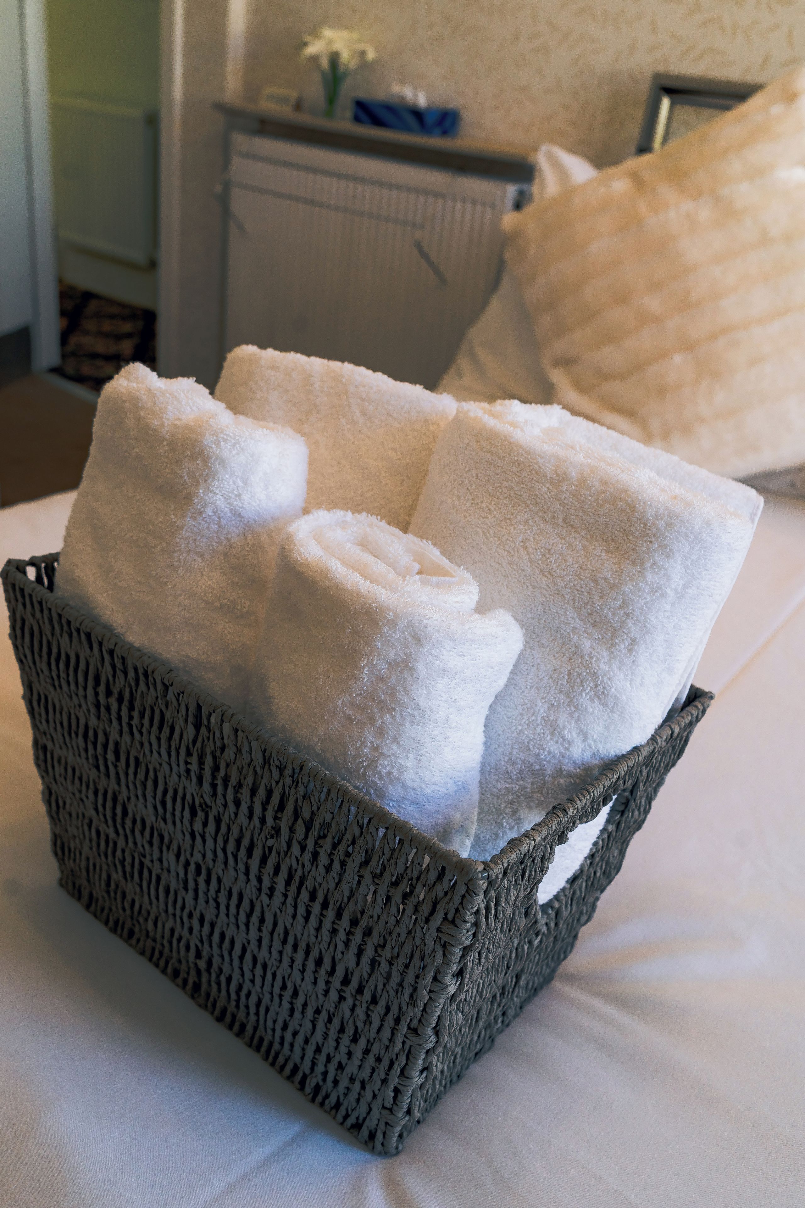 Un panier contenant des serviettes blanches soigneusement pliées, posé sur un lit.