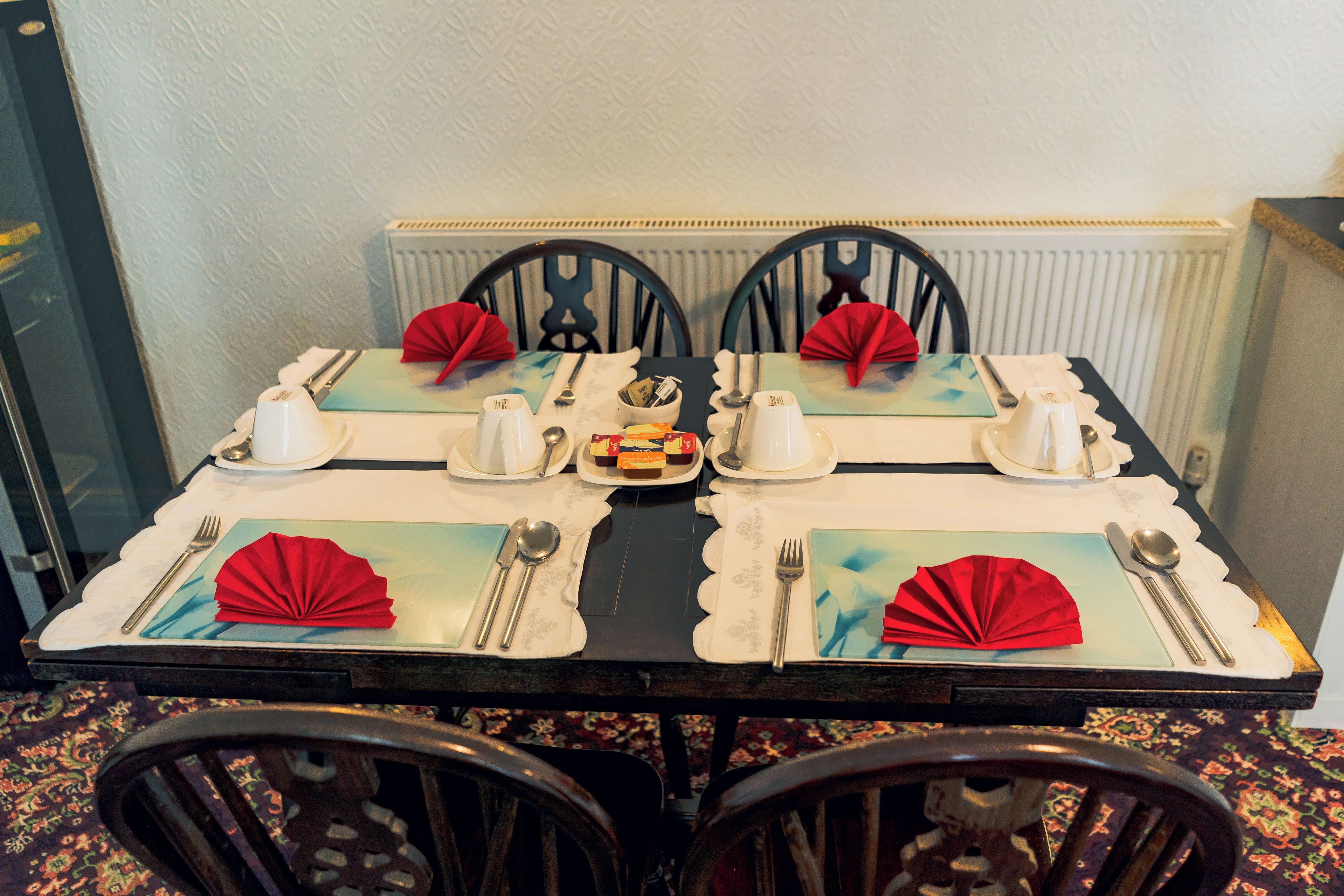 A dining table set for four with a central decorative item, surrounded by chairs.