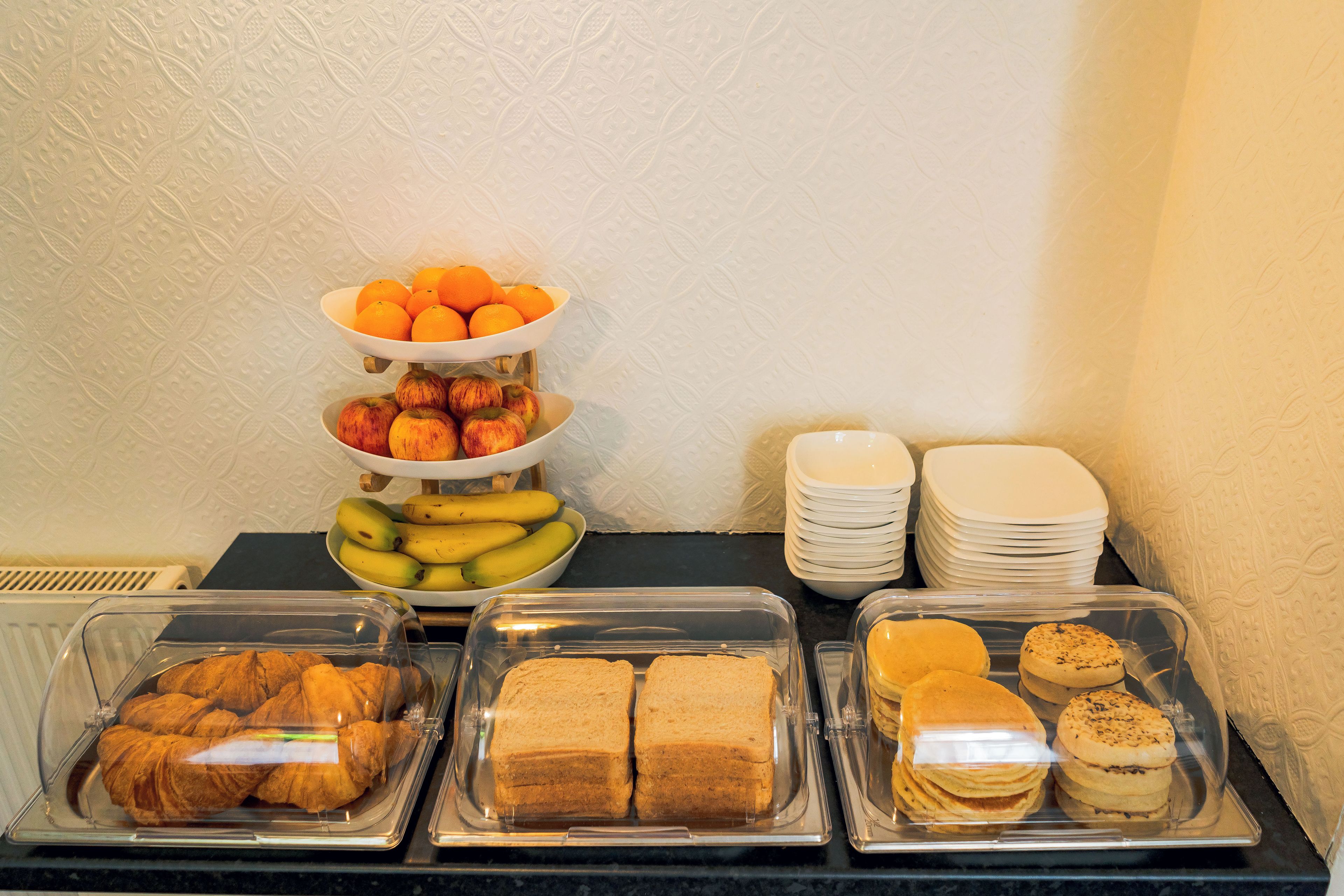 A buffet with trays of pastries, sandwiches, and fruits.