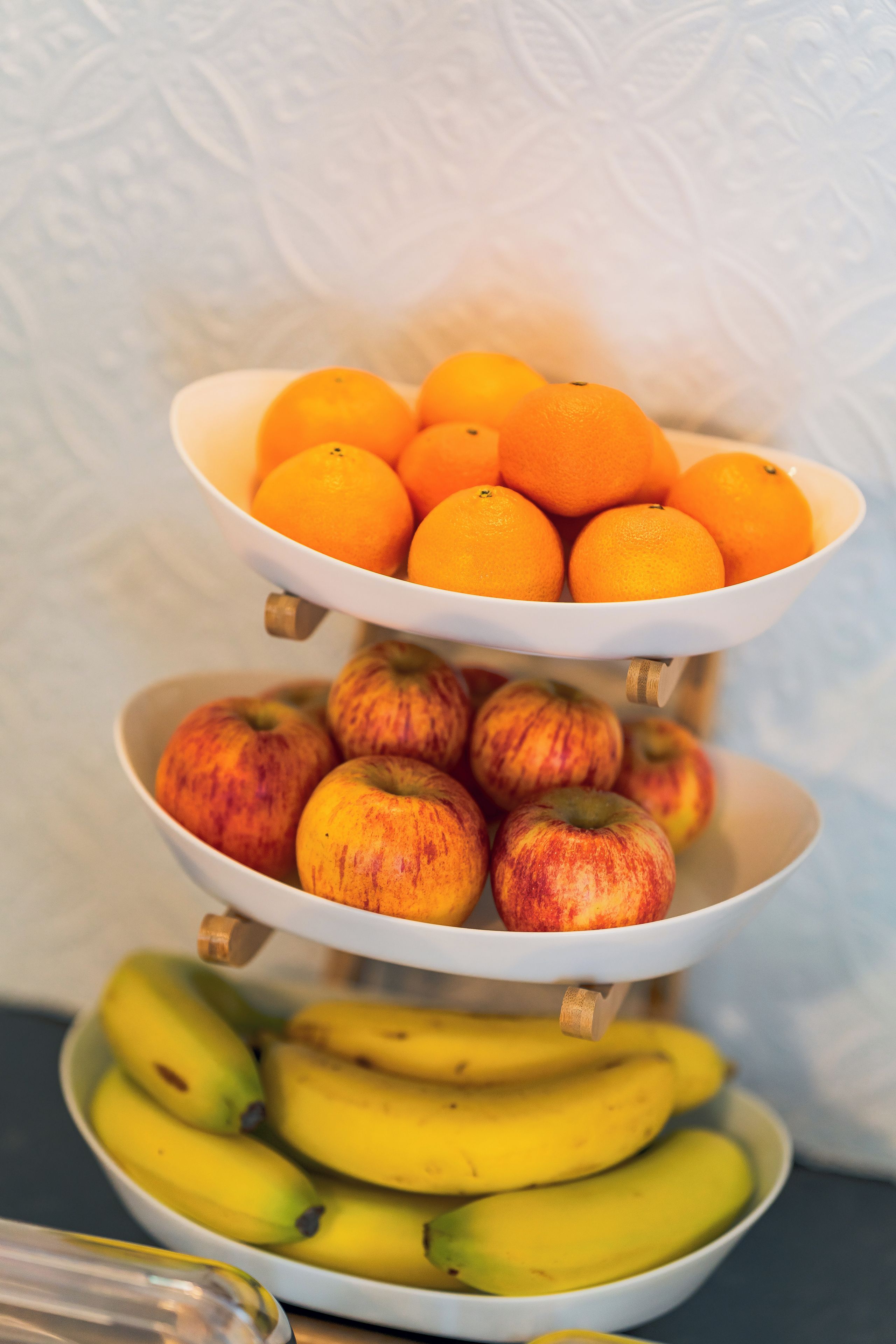 Ein mehrstöckiger Obststand mit Orangen, Äpfeln und Bananen.