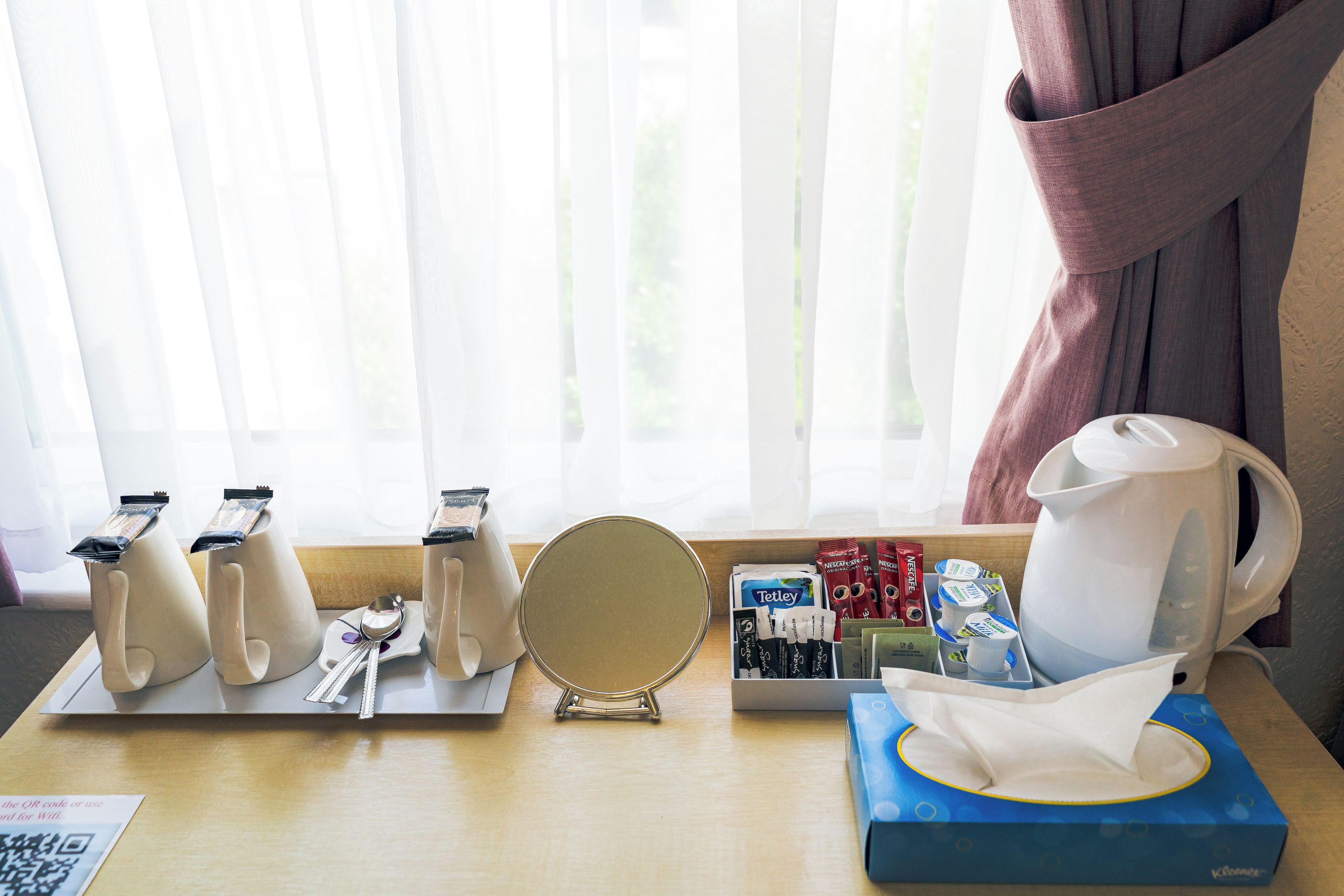Una preparación para desayuno con cafetera, tetera y diversos alimentos envasados sobre una mesa.