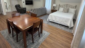 Una habitación amplia con una mesa de comedor, un sofá, una cama y un ventilador de techo.