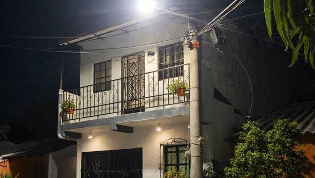 Una casa de dos pisos con balcón, garaje y plantas en macetas.