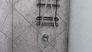 Ducha con cabezal de ducha de mano y panel de control en la pared.
