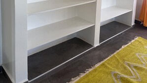 A room with two white shelving units against a wall, a dark floor, and a yellow rug with a pattern. -  2Bdr zen villa private pool + cleaning (Diani Beach)