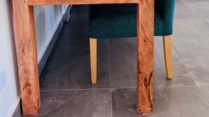 A wooden table with colorful paintings on the left, a laptop on it, and a chair with a green cushion. -  2Bdr zen villa private pool + cleaning (Diani Beach)