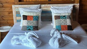 Quarto estilo cabana de madeira com uma cama, duas almofadas e duas toalhas.