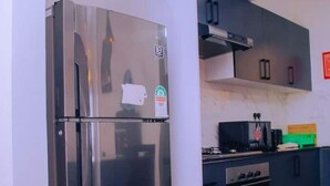 Eine moderne Küche mit einem Edelstahl-Kühlschrank, einem Einbauofen und dunklen Schränken.