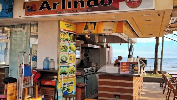 Ein Restaurant am Meer mit Terrassensitzgelegenheiten, einer Speisekarte und Blick auf den Ozean.