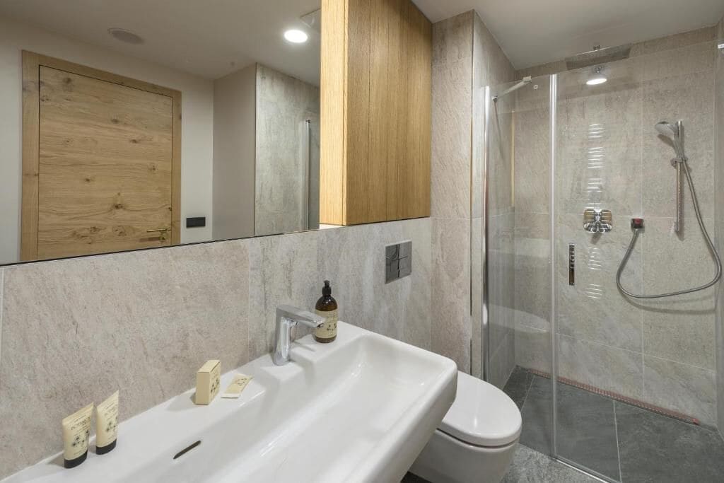 Un baño moderno con un lavamanos grande, inodoro y zona de ducha con mampara de vidrio.