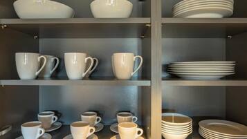 Un ensemble d’étagères avec des tasses et des soucoupes blanches, ainsi que des assiettes empilées.