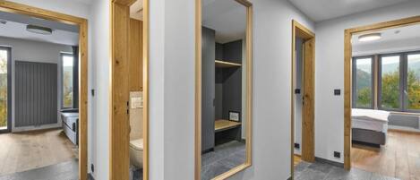A modern interior with a large mirror, wooden door frames, and a view of a bed and window.