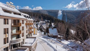 Ein Hotel namens "Palace" mit modernem Design, verschneiter Landschaft und Blick auf ein Tal.