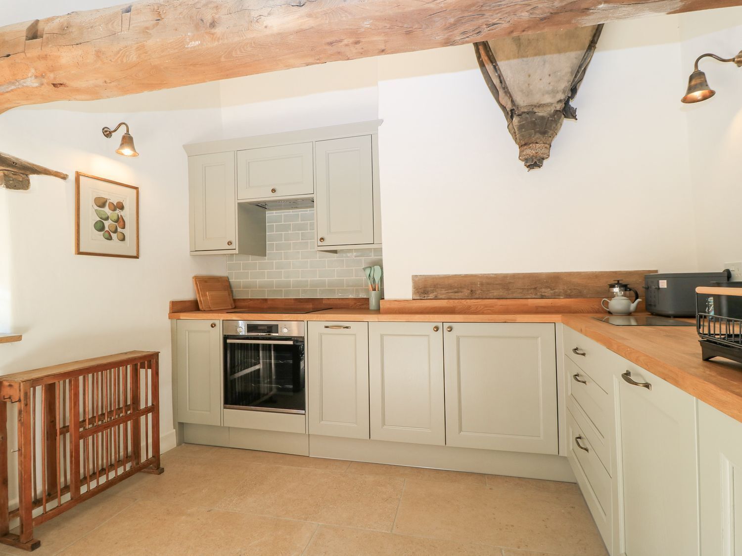 A kitchen with white cabinets, a wooden countertop, a built-in oven, and a hanging light fixture.