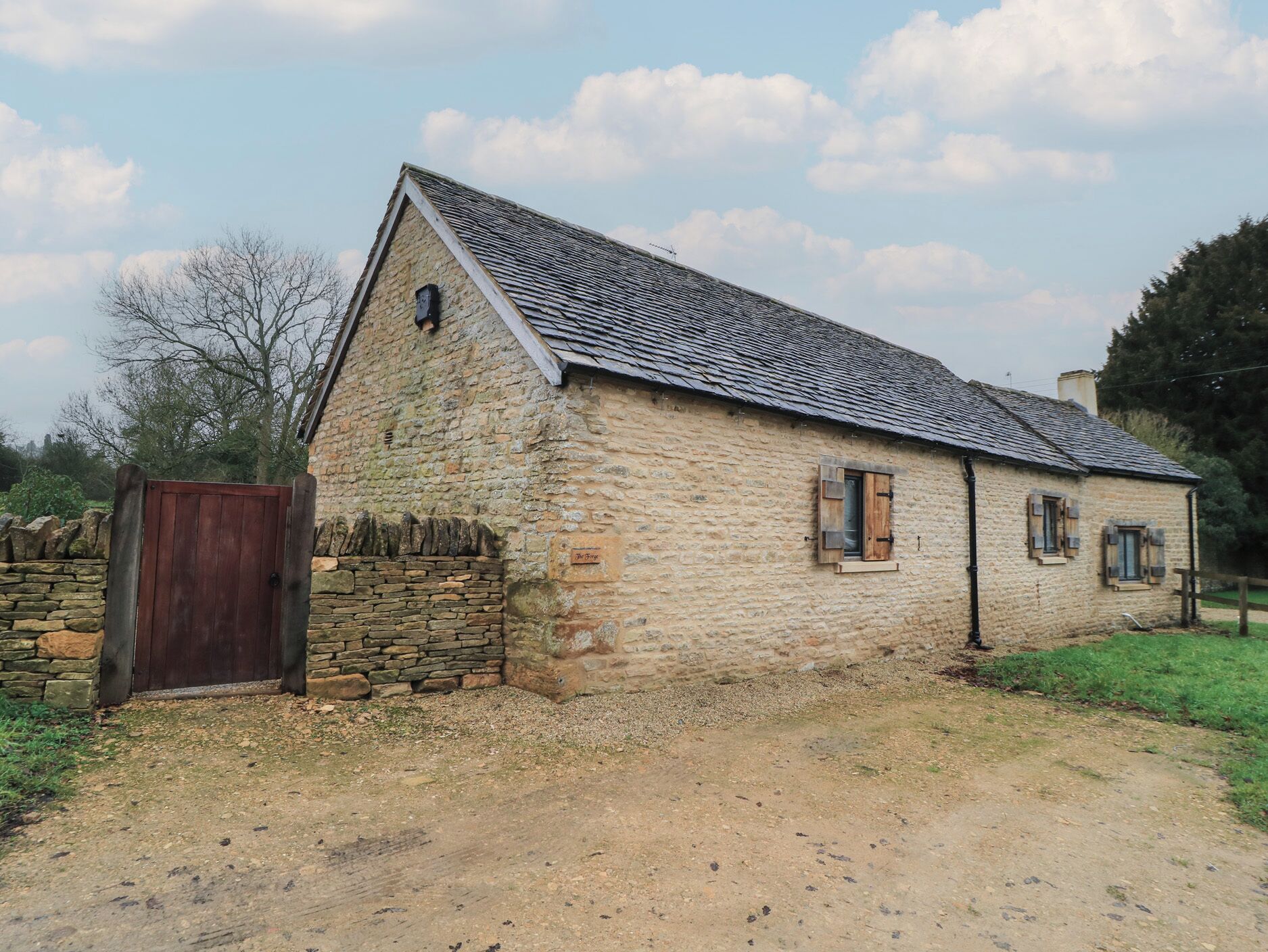 A stone building with a sloped roof, a wooden door, and a small window with shutters.