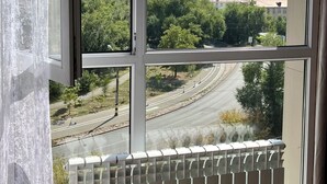 Une pièce dotée d’une grande fenêtre donnant sur un paysage urbain, avec des immeubles et une route.