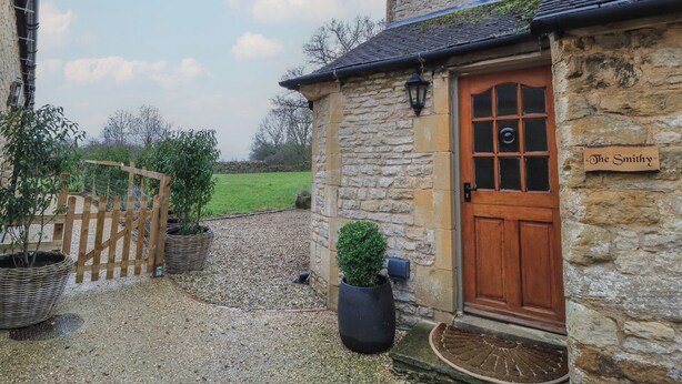 A stone building with a wooden door and a sign reading "The Smithy". - The Smithy (Moreton-in-Marsh)