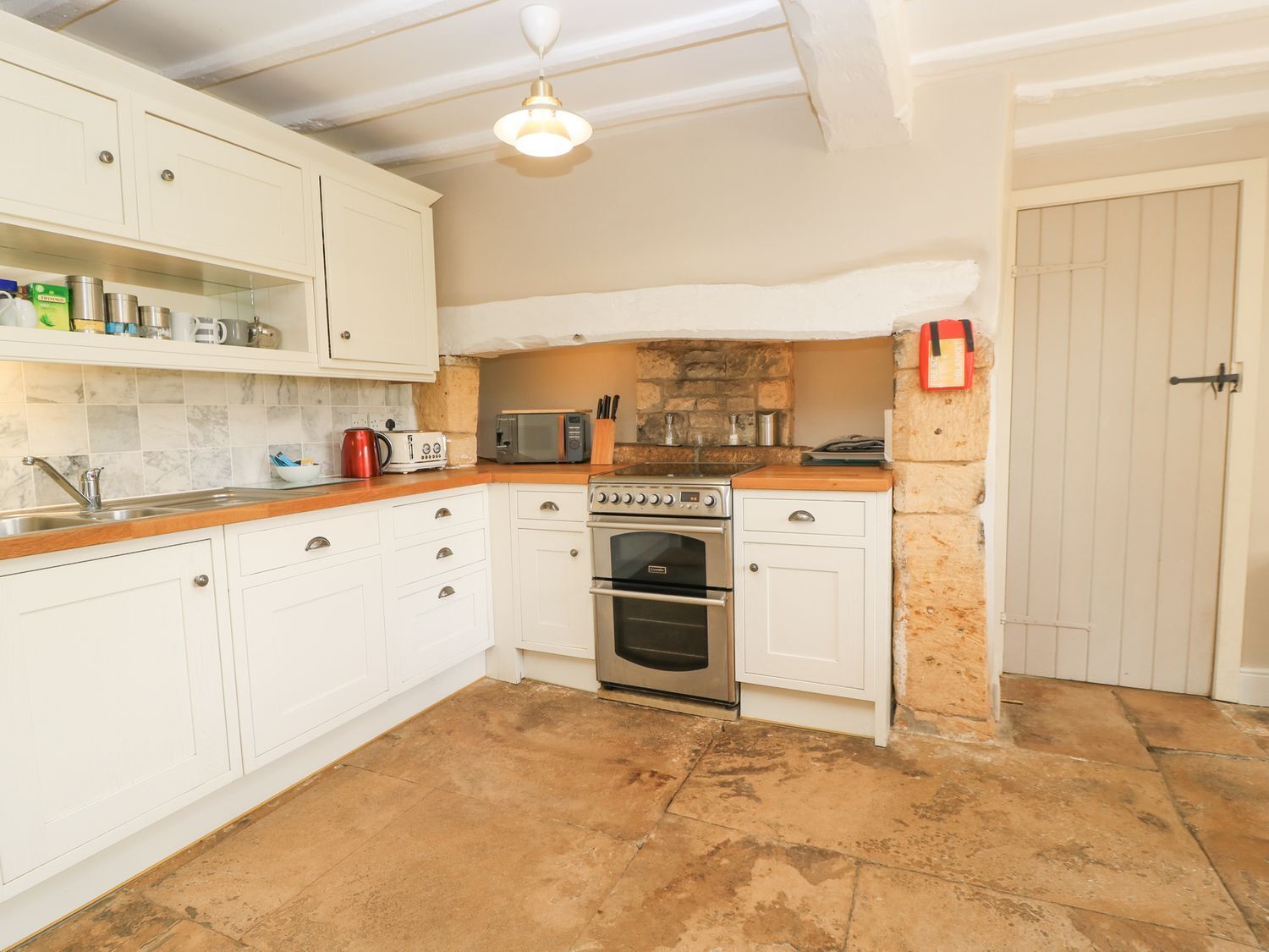 A compact kitchen with white cabinets, a built-in oven, a microwave, and a coffee maker.