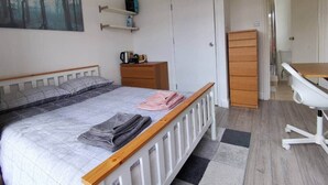 A bedroom with a bed, a desk, a wardrobe, and a painting on the wall. - Double bedroom with ensuite 1 stop to Excel and O2 (London)