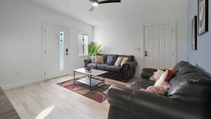 A living room with a dark leather sofa, a coffee table, and a ceiling fan. - Cozy One Bedroom Oldtown EV Charger Shared Space (Scottsdale)