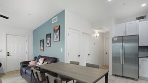 A modern kitchen with white cabinets, a stainless steel refrigerator, and a dining area with a wooden table and chairs. - Cozy One Bedroom Oldtown EV Charger Shared Space (Scottsdale)