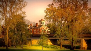 A large, historic building with a prominent tower and multiple chimneys, surrounded by lush greenery and trees. - Luxury, Golf-Themed Townhome (Galena)