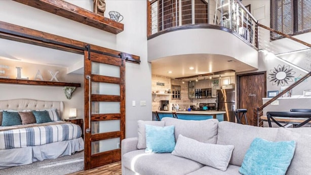 A spacious living area with a sofa, a bed, and a wooden ladder leading to a loft. - Luxury, Golf-Themed Townhome (Galena)
